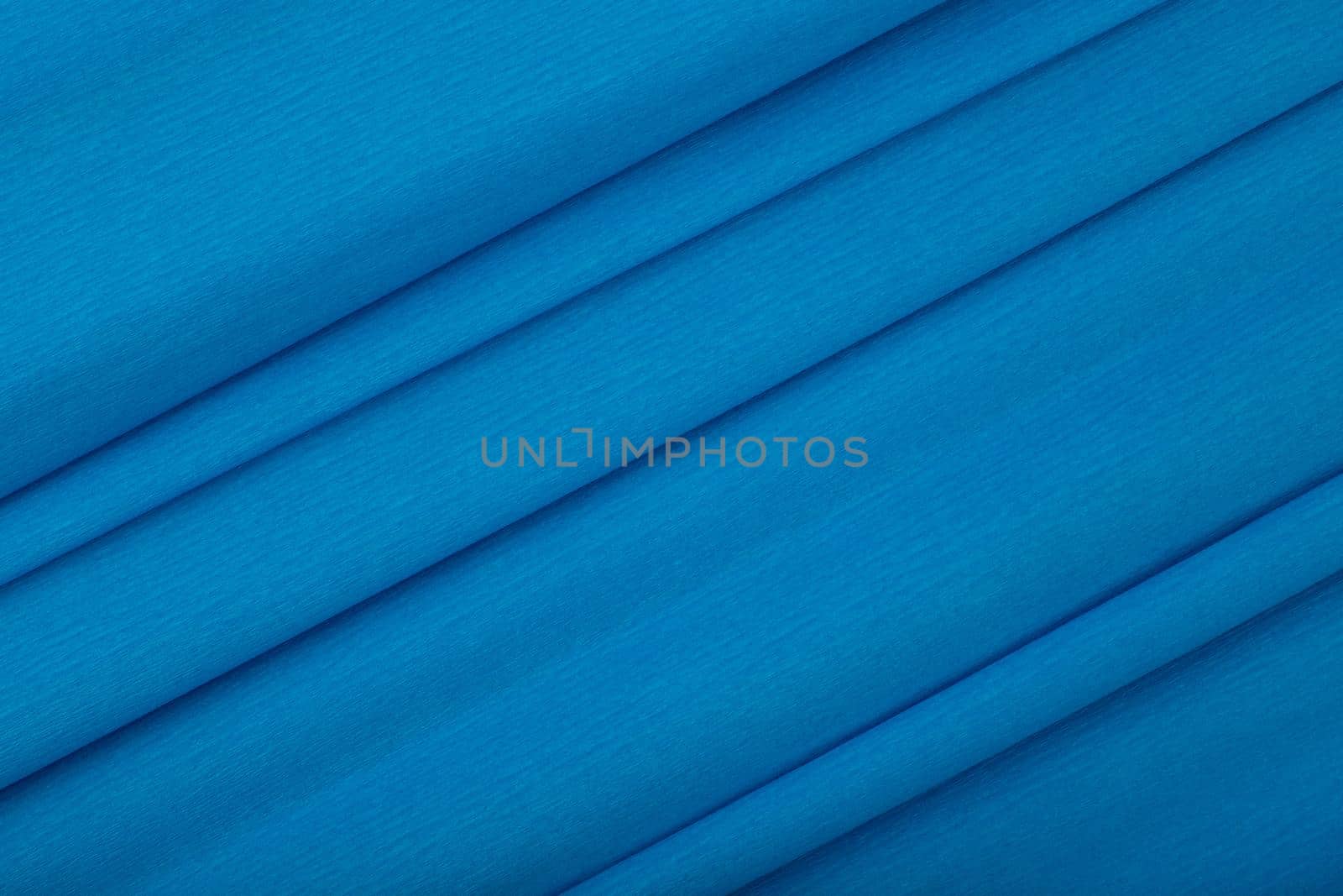 Abstract saturated blue background with diagonal lines. Blue textured background with waves made of corrugated paper. Concept of template for advertising or banner with copy space