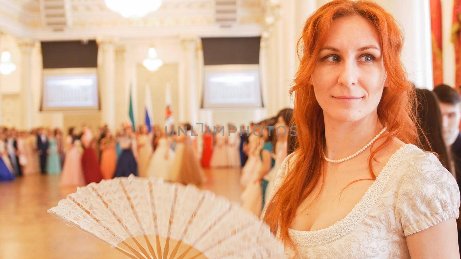 Young woman in vintage ball costume woman waving a fan, close up