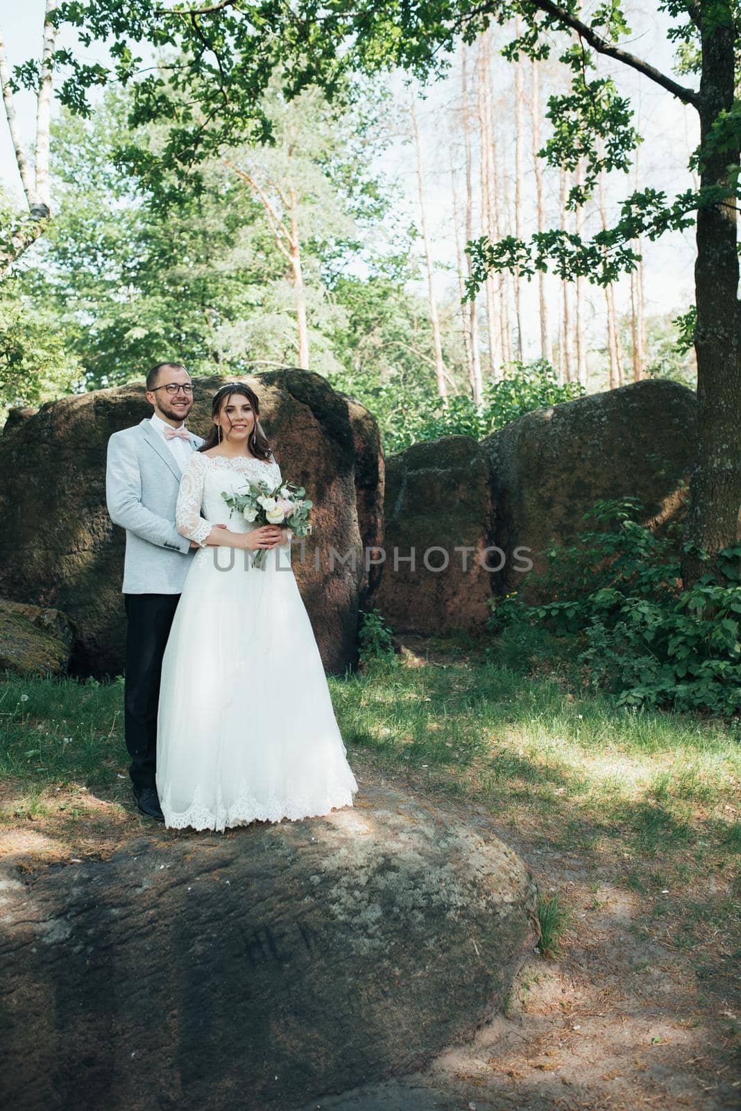 Wedding photo of the bride and groom in a gray-pink color on nature in the forest and rocks. by lunarts