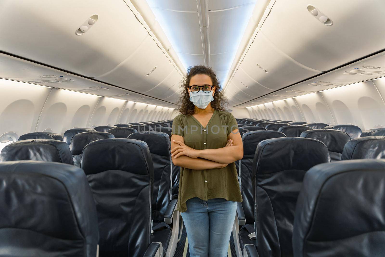 Adult woman in protective mask with her arms crossed on the plane. Quarantine concept