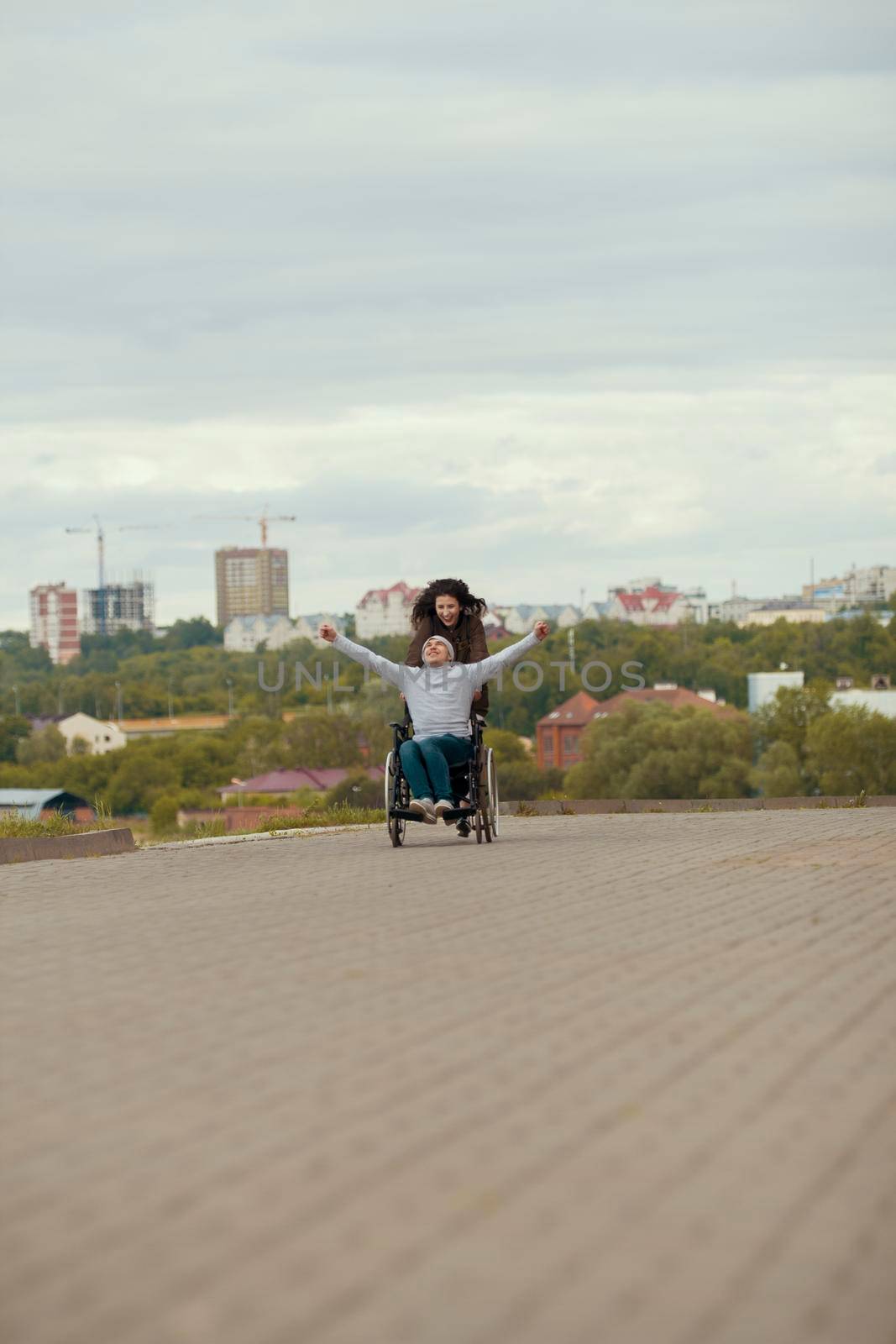 Young woman with happy disabled man in wheelchair having fun outdoors, close up