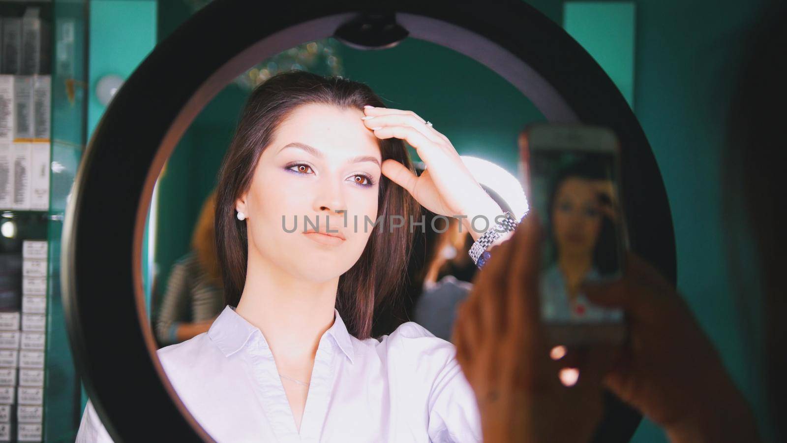 Female hands shooting on the phone makeup of model with backlight, close up