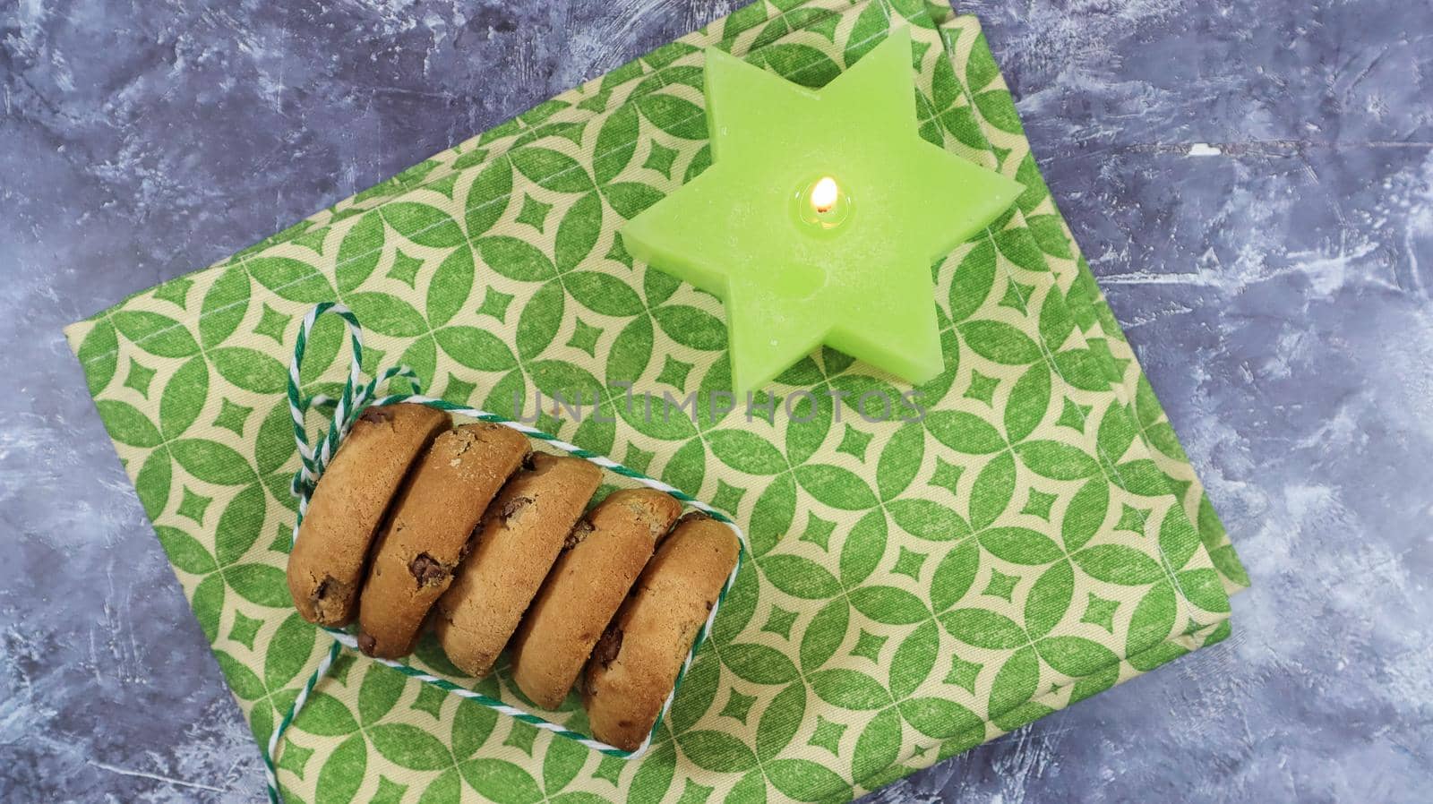 American chocolate chip cookies in a stack tied with thread on a green napkin and a candle. Traditional rounded crunchy dough with chocolate chips. Bakery. Delicious dessert, pastries