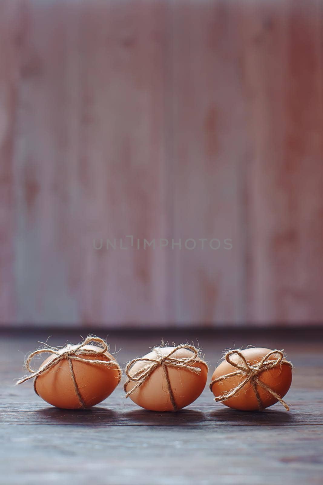 Easter beige eggs decorate with rope on brown wooden background with copyspace