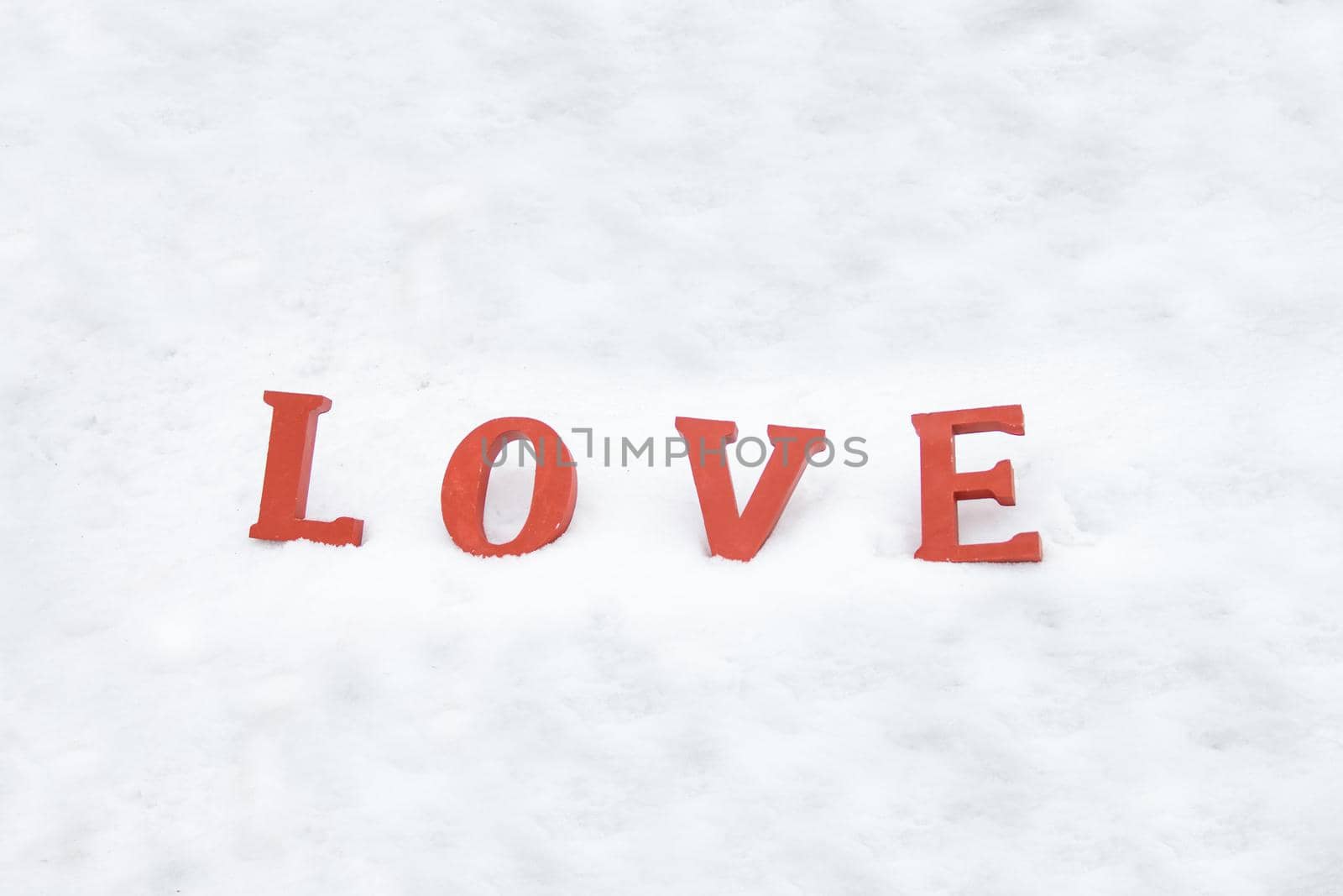 red love letters on white snow. word love on white background about-valentine friends or lovers day by julija