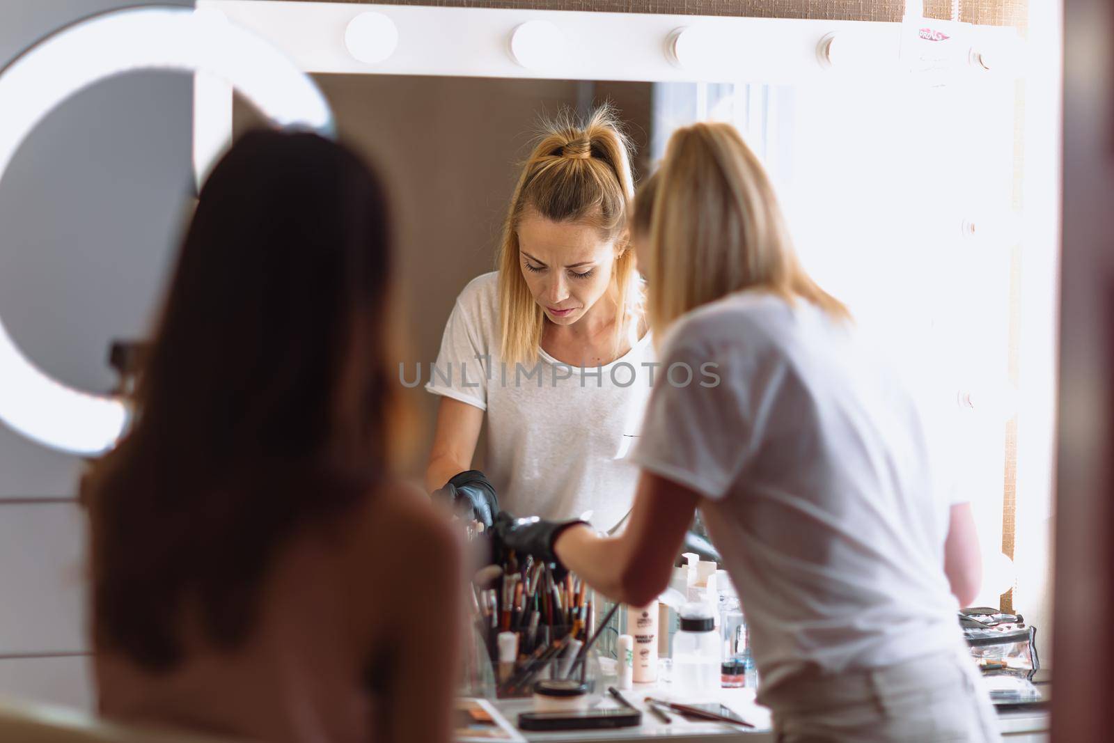 Makeup woman artist at work, professional in action with young model in beauty salon and creative classes