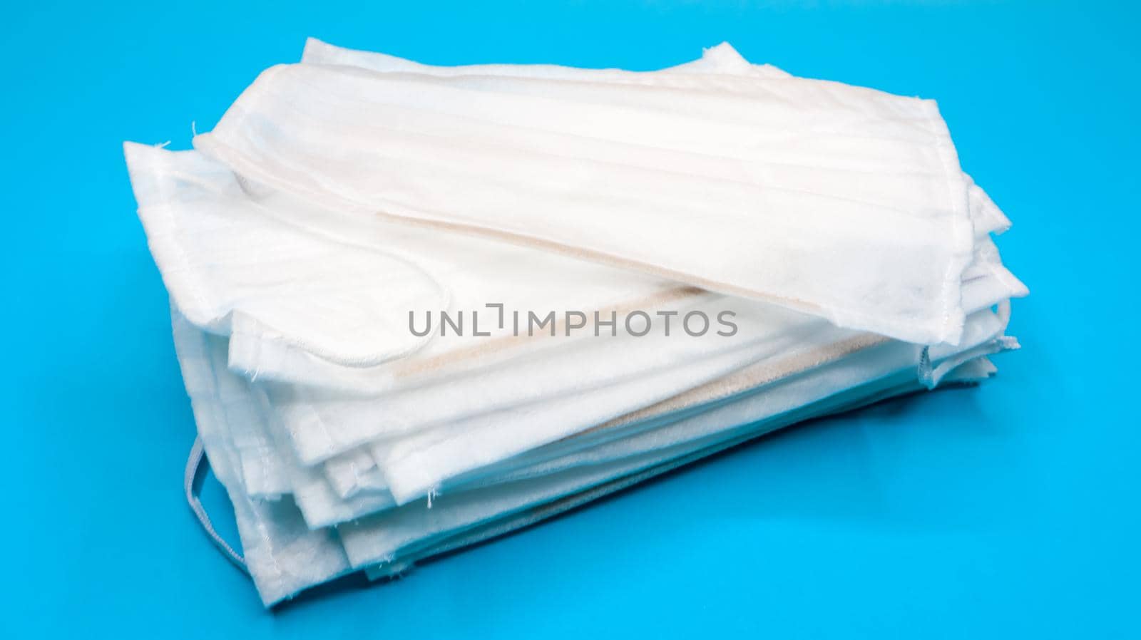 Coronavirus protection. Antiviral protective medical face masks with ear loops. Surgical mask background. Respiratory syndrome, coronavirus disease COVID-19. Many folded medical masks