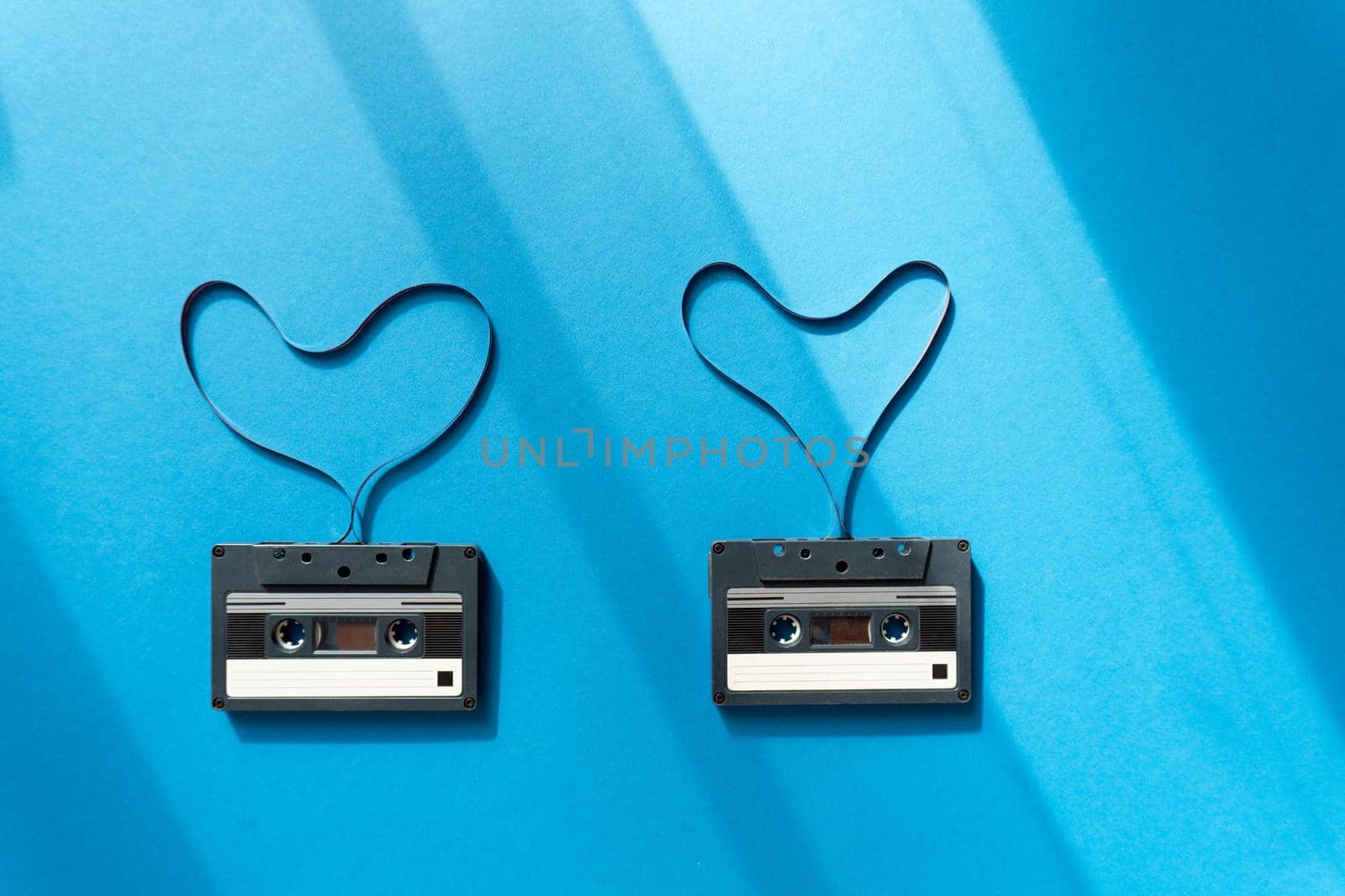 cassettes with magnetic tape in the shape of heart on blue background by uveita
