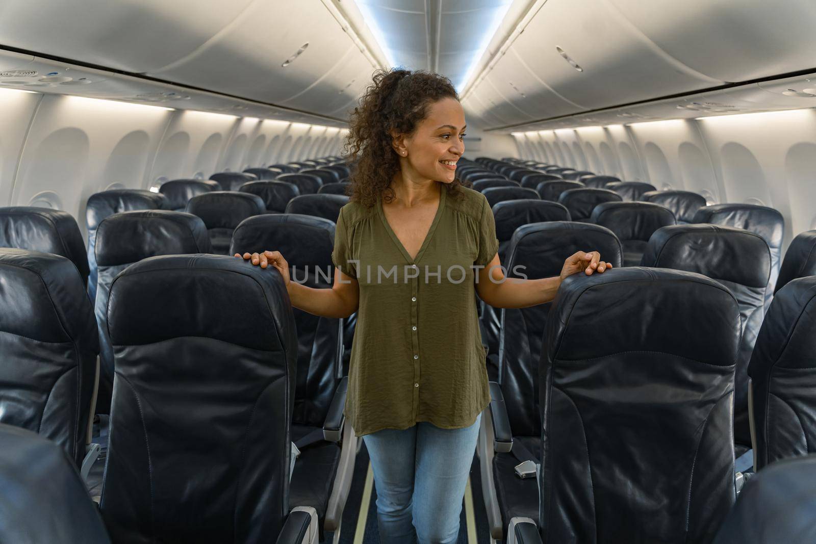 Happy pretty woman standing in the plane near the seats by Yaroslav_astakhov