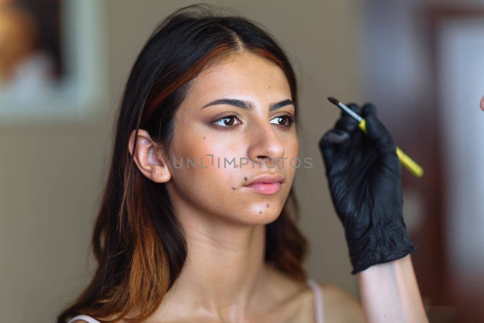 Beautiful model in make up process. Portrait of young pretty woman with beutiful makeup in beauty studio salon. Evening make up, blurry background