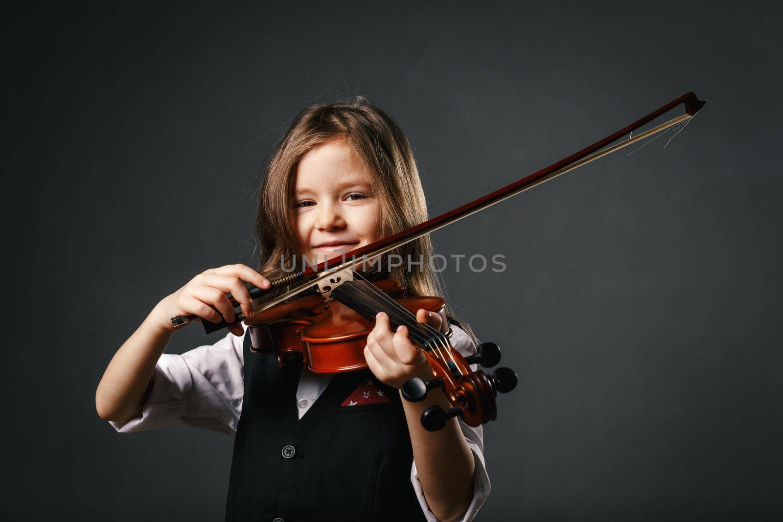 Beautiful smiling girl with long hair playing violin