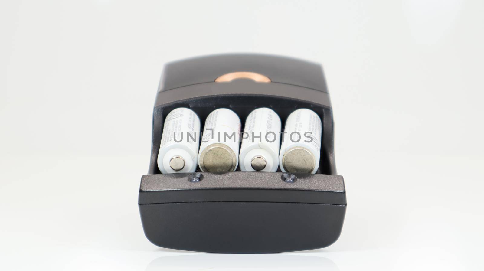 Fast charging of AA batteries. Rechargeable batteries in a black charger with four battery cells on a white background