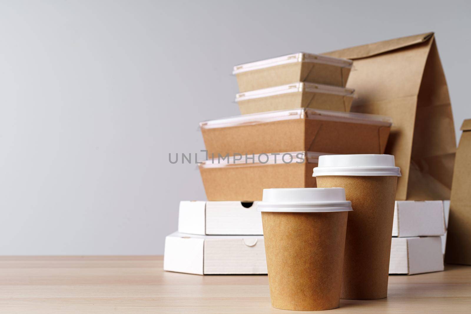 Many various take-out food containers, pizza box, coffee cups and paper bags on light grey background. Food delivery