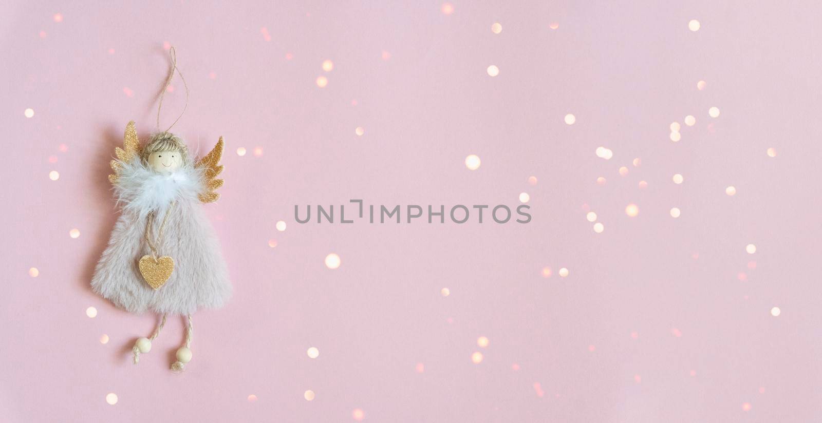 Christmas angel tree toy on pastel pink background, bokeh, copy space, top view, new year mood, magic concept.