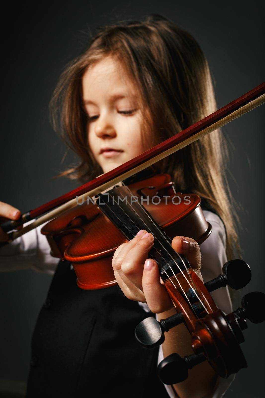 Beautiful girl with long hair and closed eyes playing violin