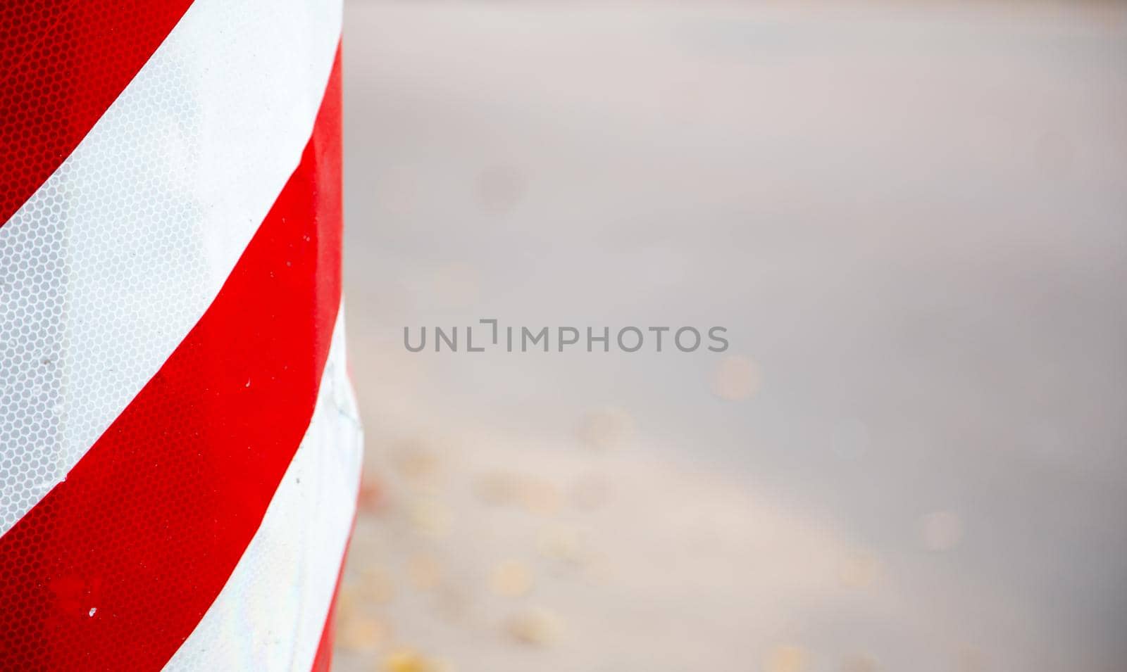 Red and white striped concrete road barrier close up with copy space for text.