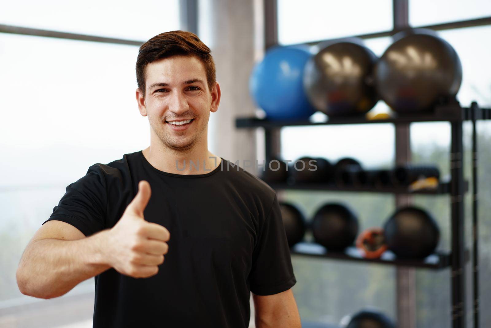 Portrait of a young handsome fitness trainer in a gym, close up