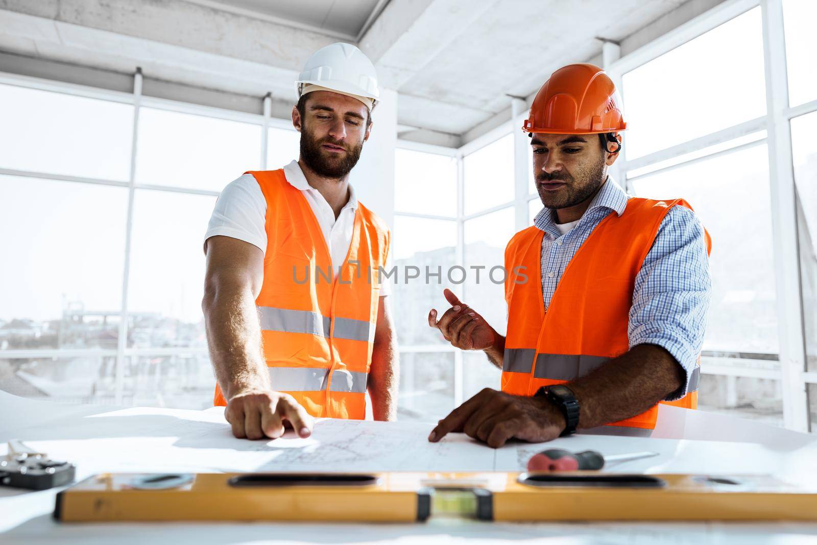 Two young engineers man looking at project plan on the table in construction site