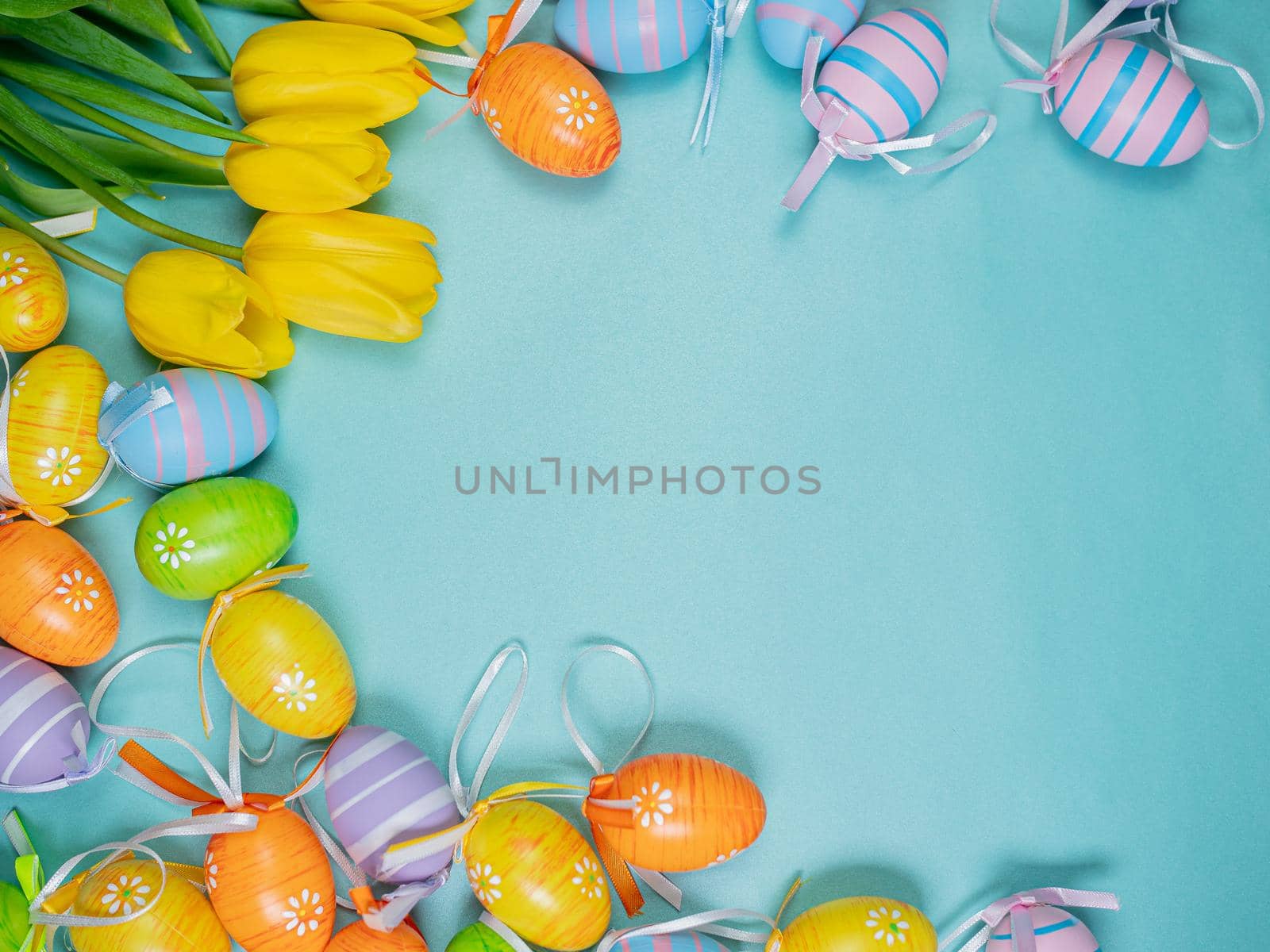 Multicolored painted Easter eggs with tulips on a beautiful blue background. Easter holiday concept.