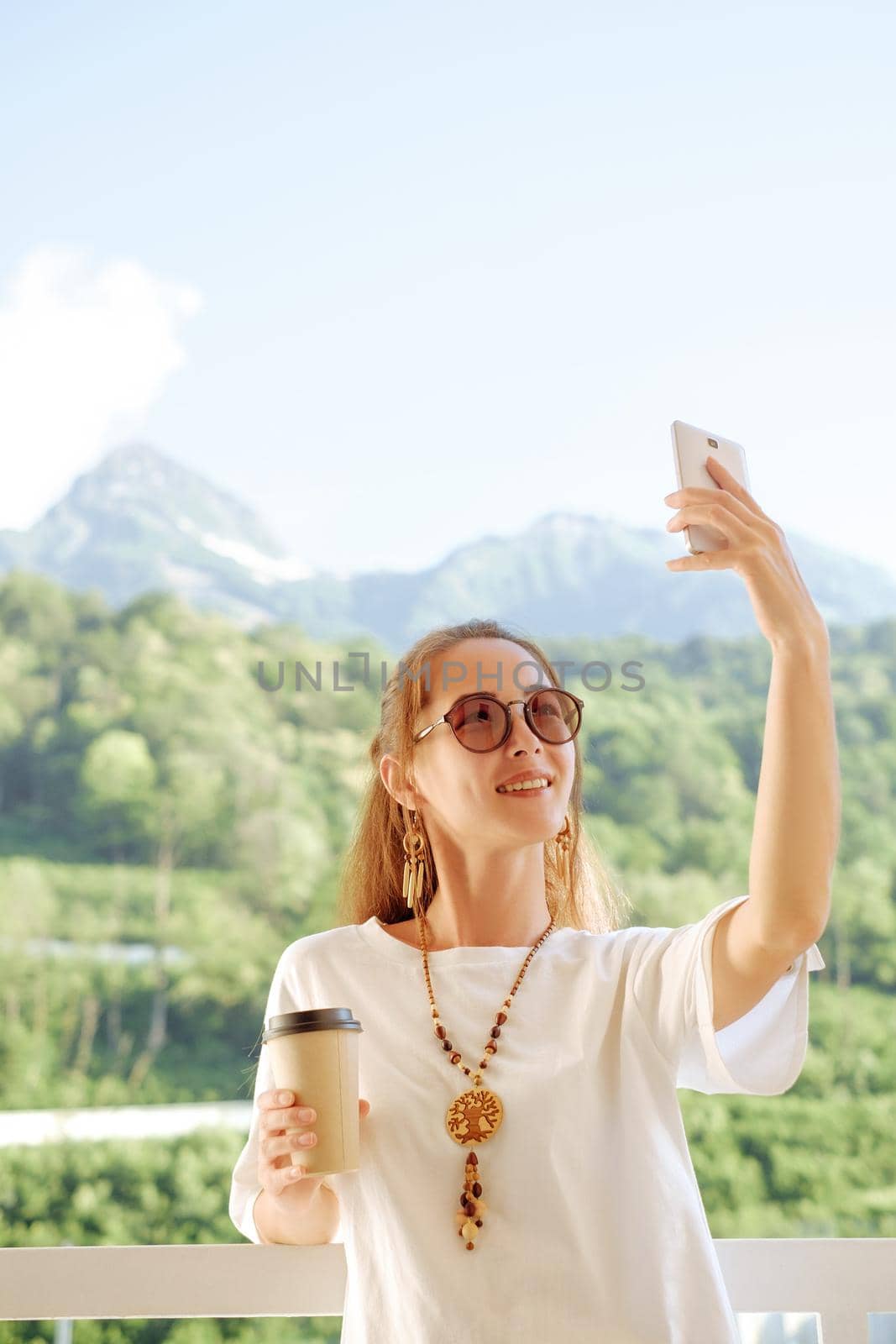 Happy woman taking selfie photo on background of summer mountains. by alexAleksei