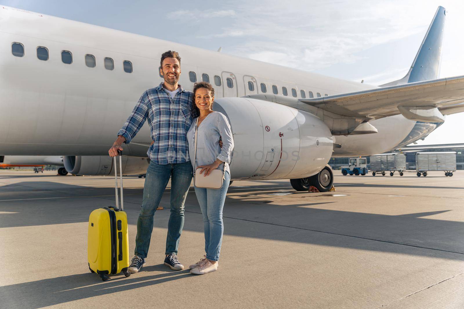 Full length photo of adult couple standing near the plane and going to travel. Trip concept