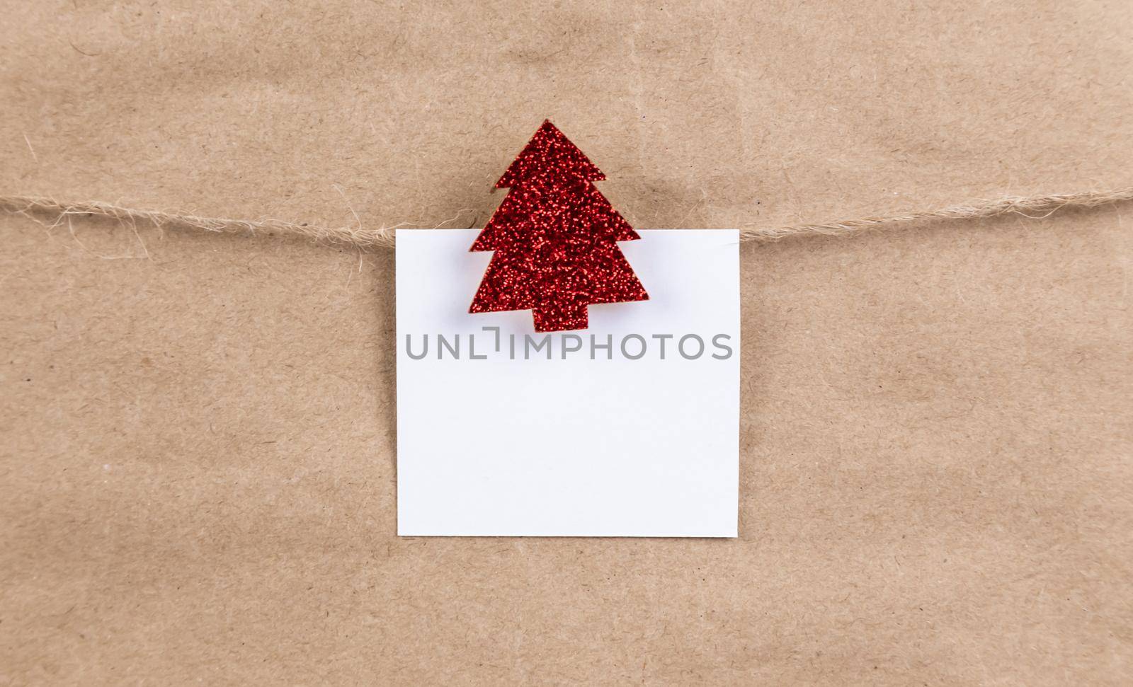 paper sticker hanging on a rope on wooden red glitter christmas tree clothespin. Christmas decoration. Christmas card.