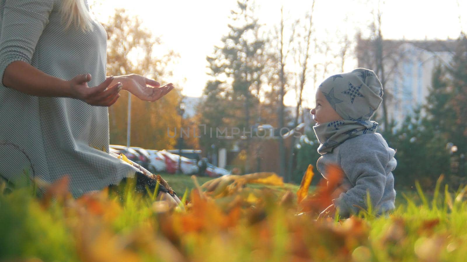 Young mother with her laughing little baby in autumn park. Close up