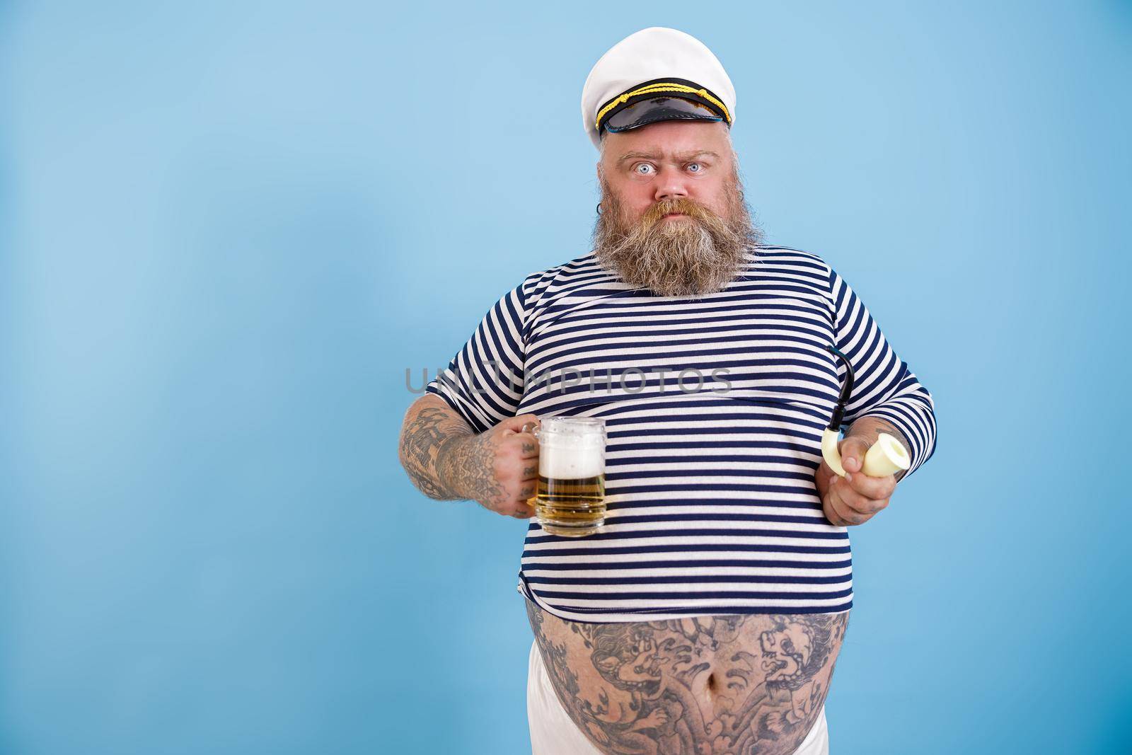 Funny obese sailor holds smoking pipe and beer grimacing on light blue background by Yaroslav_astakhov