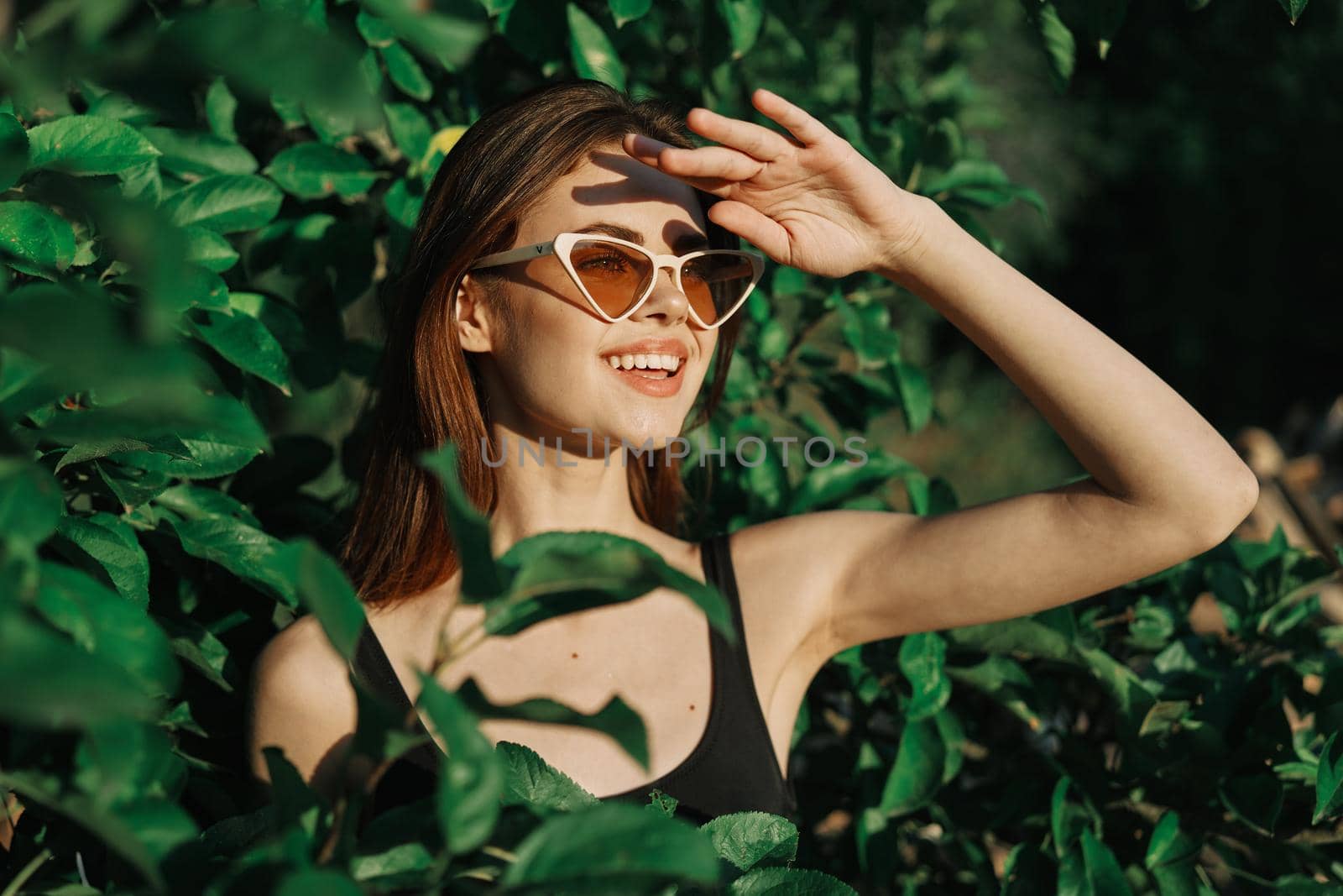 smiling woman wearing sunglasses green leaves nature fashion. High quality photo