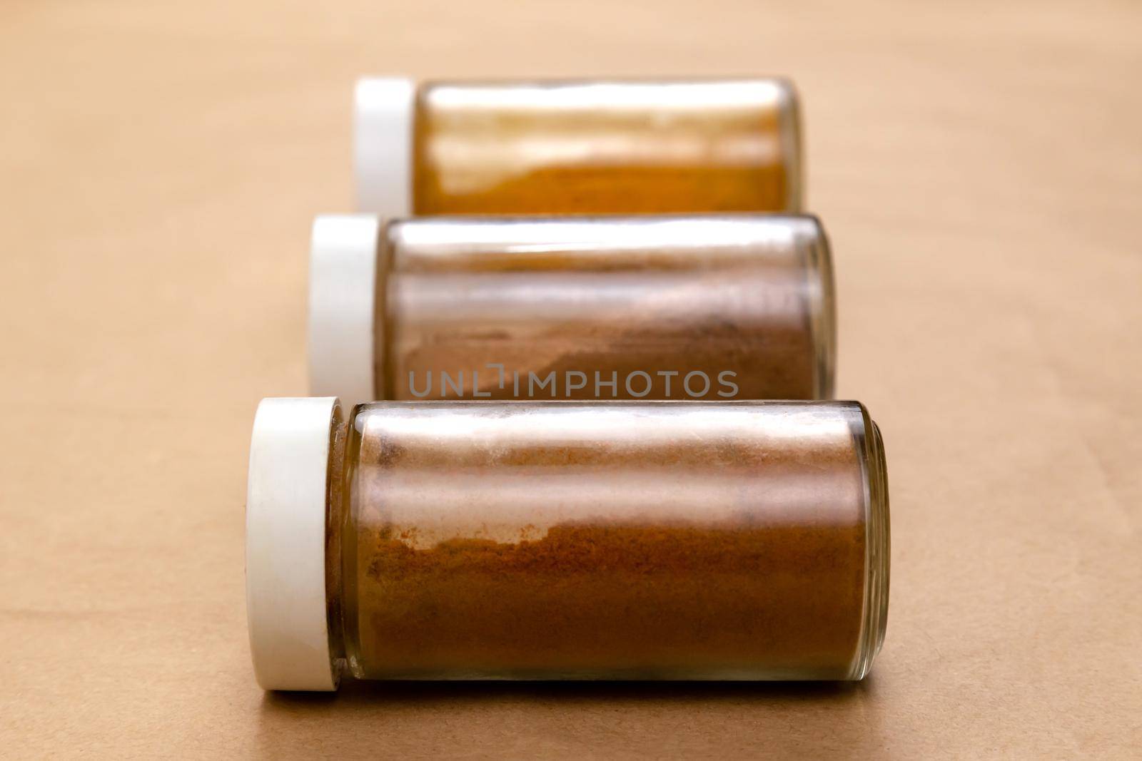 Three jars of seasoning on a brown background with selective focus