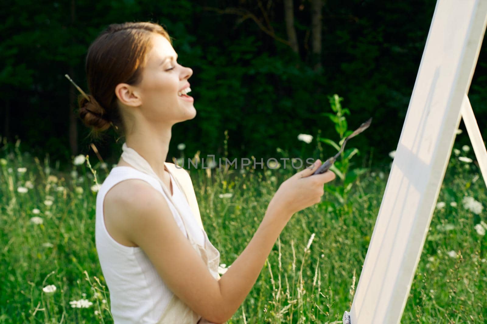 woman artist outdoors with palette of paints paints a picture. High quality photo