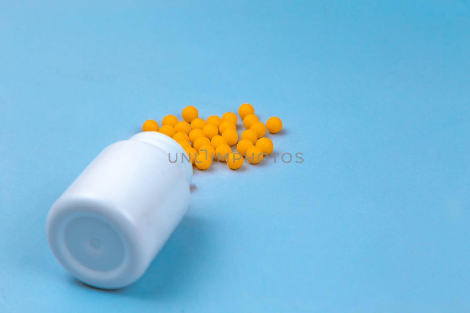 Yellow pills and plastic white bottle. Blue background with copy space for text. by lunarts