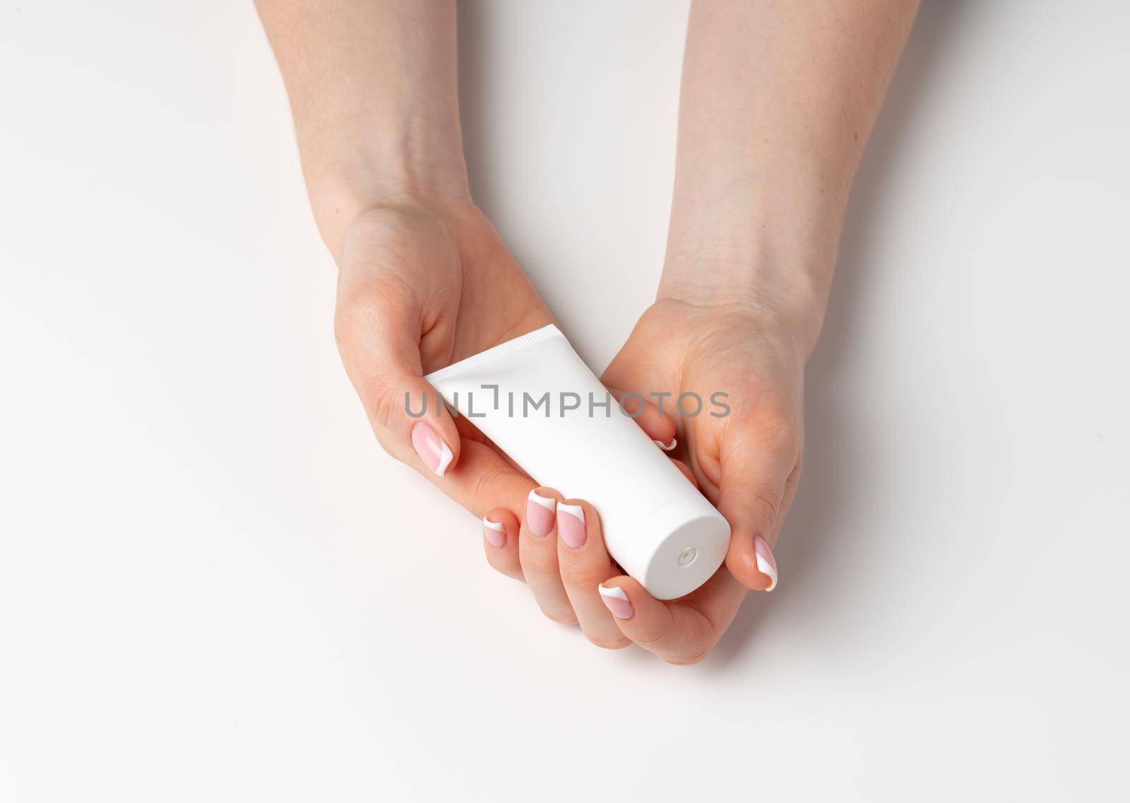 Female hand holding cosmetic bottle on white background