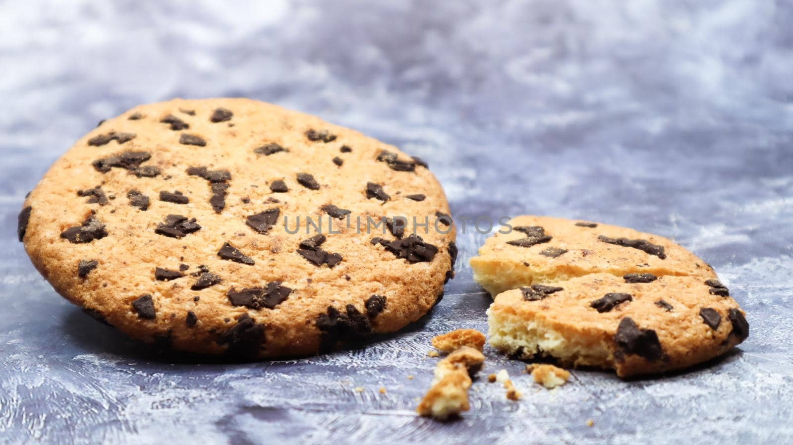 One soft, freshly baked chocolate chip cookie on a gray marble kitchen countertop. American traditional dessert. Delicious sweet food. Homemade baking concept for the holiday. Culinary background.