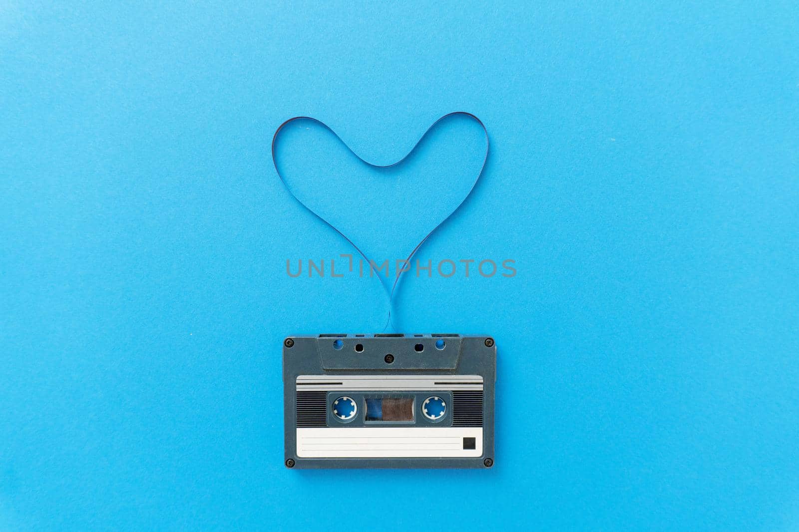 Retro audio cassete with magnetic tape in shape of heart. by uveita