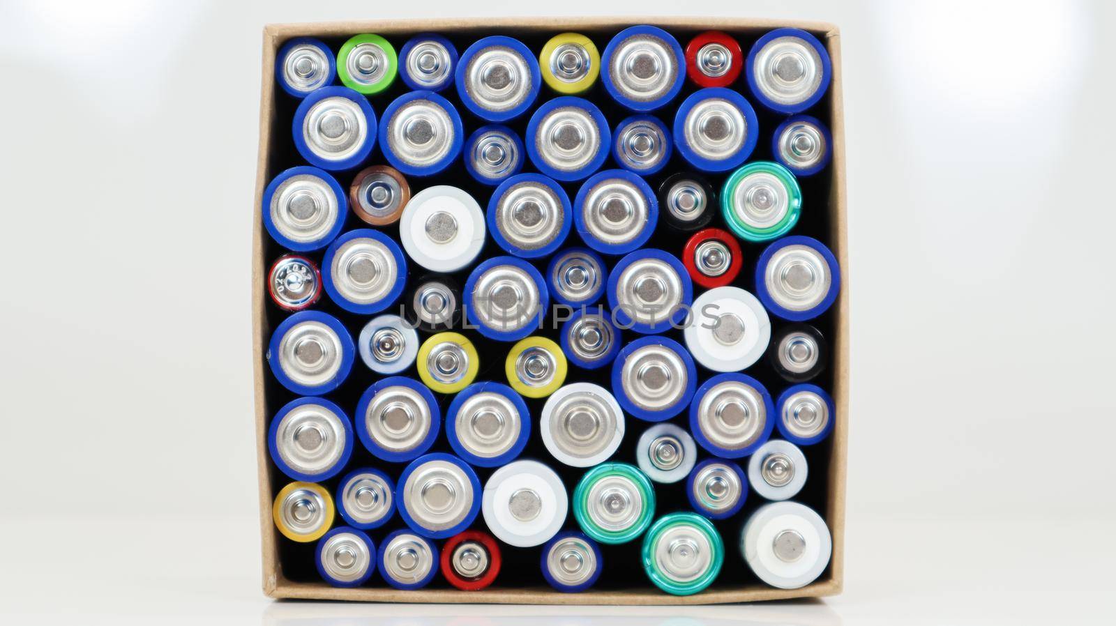 Top view of the background of AAA AA batteries and rechargeable batteries. Choice of batteries. Energy supply and recycling concept. Textures of electric elements packed close together in a box