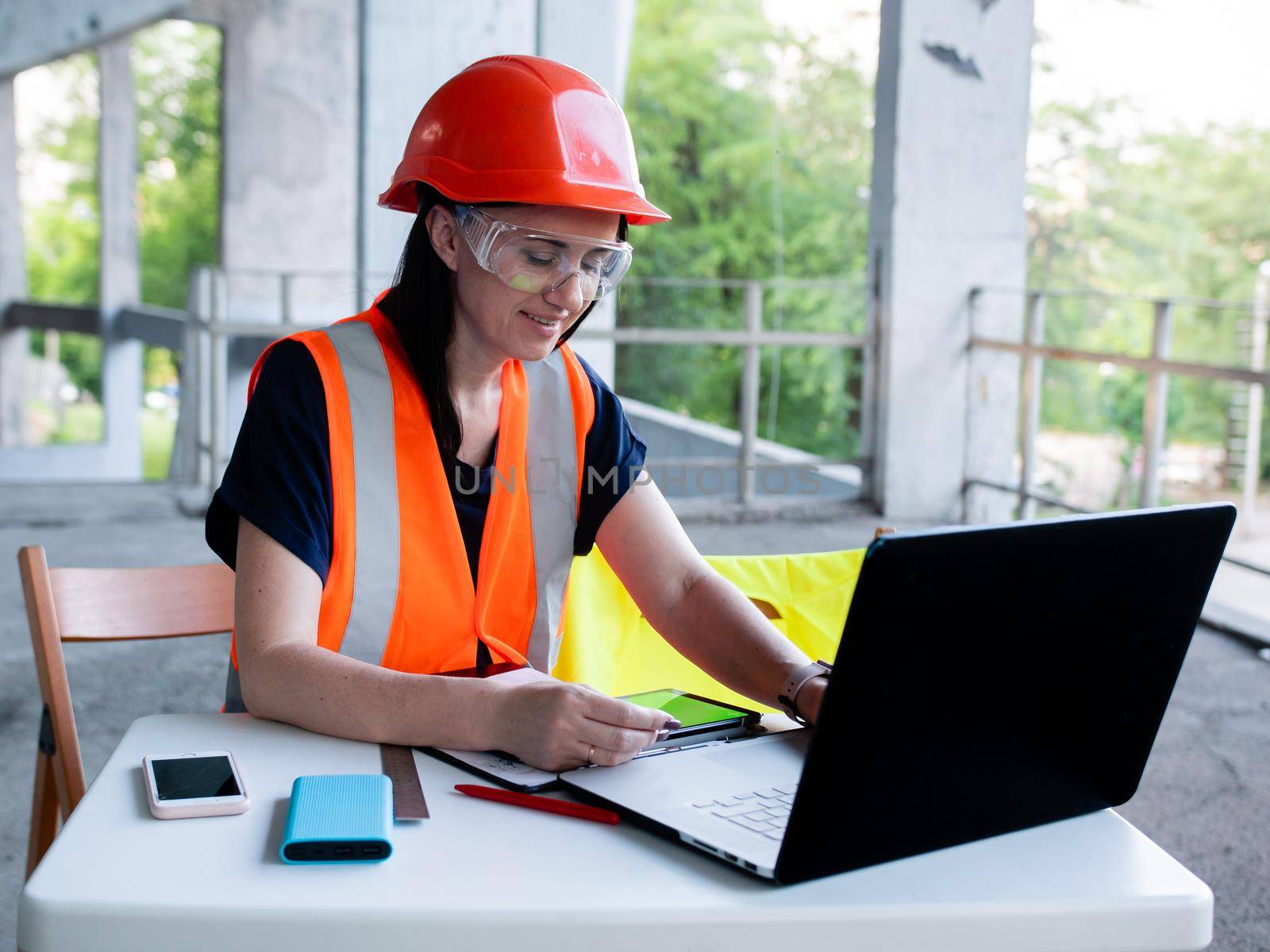 Engineer woman working on construction site examines building projects in laptop by Utlanov