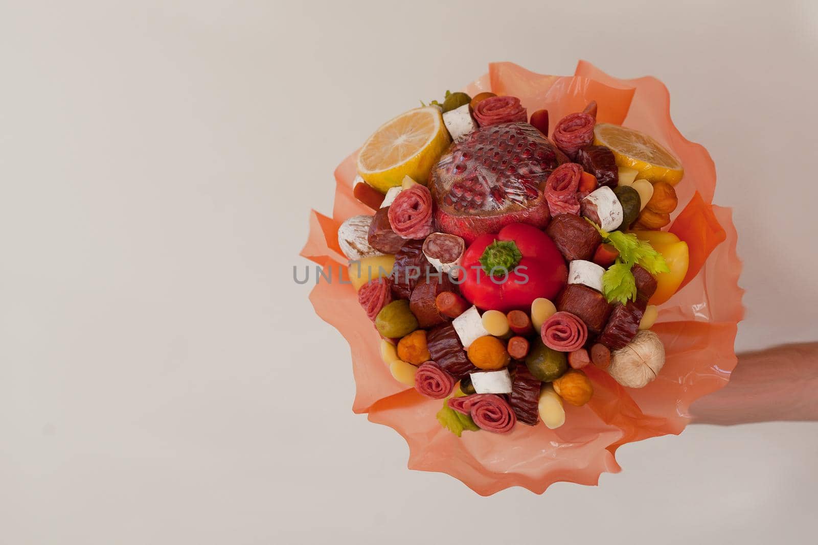 bouquet with ham. Flowers with sausages, cheese, vegetables and salami on grey background on man hand