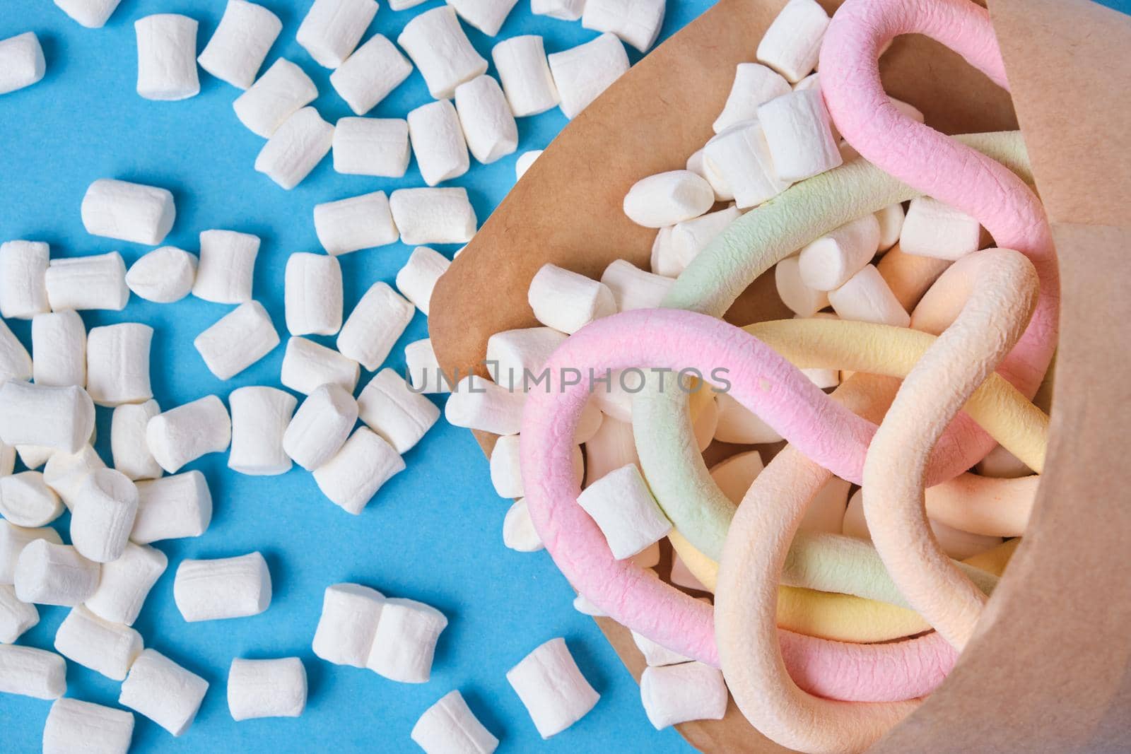 various types of marshmallows wrapped in paper on blue background by natashko