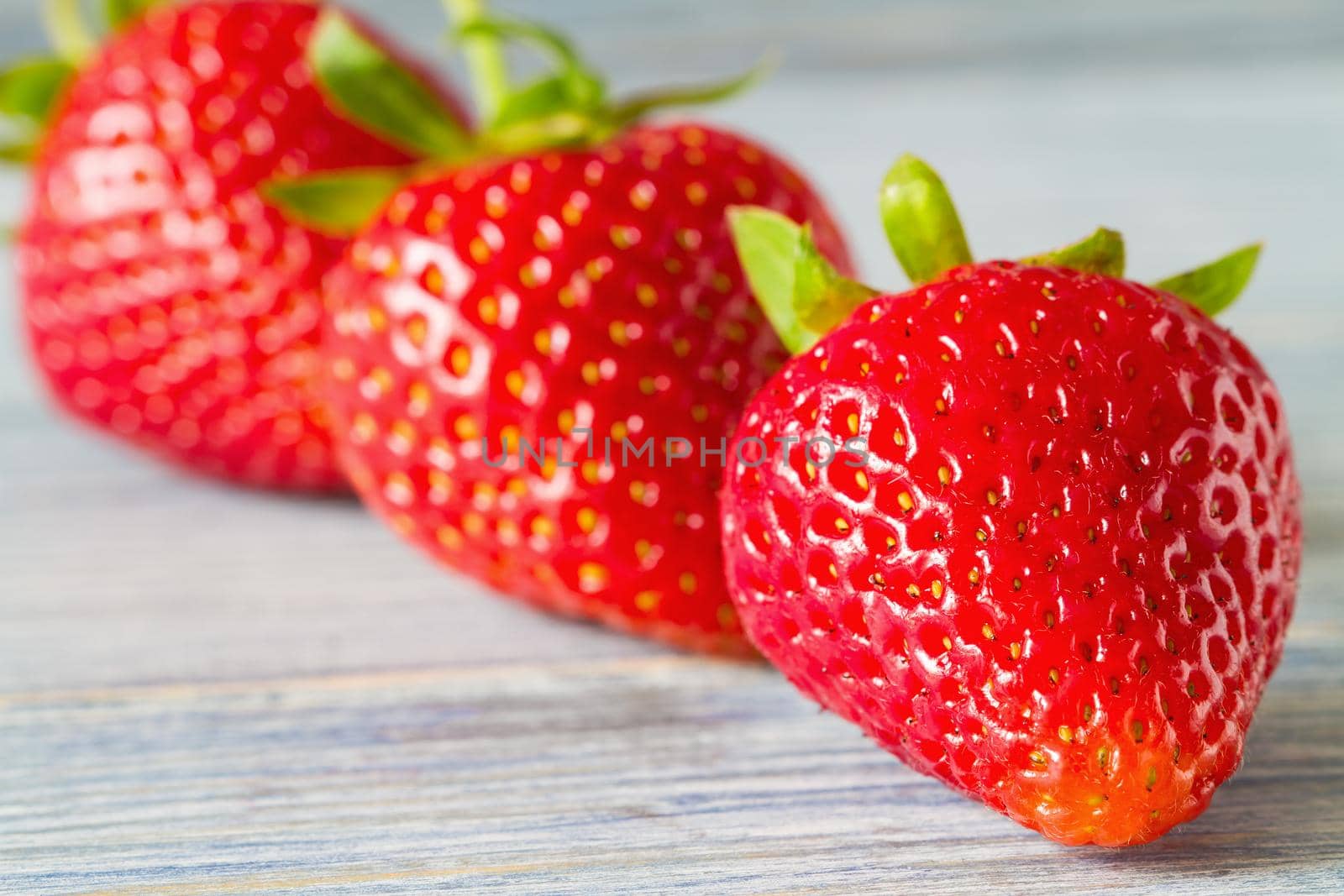 Fresh ripe strawberries on the blue wooden background. Selective focus. Closeup.