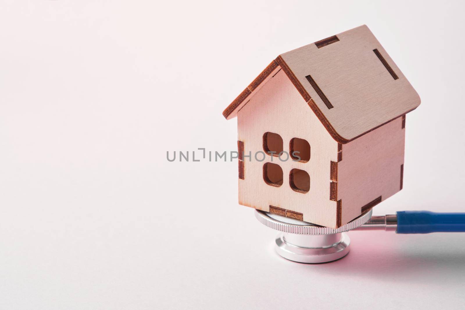 Medical stethoscope and toy house on a pink background with copy space by natashko