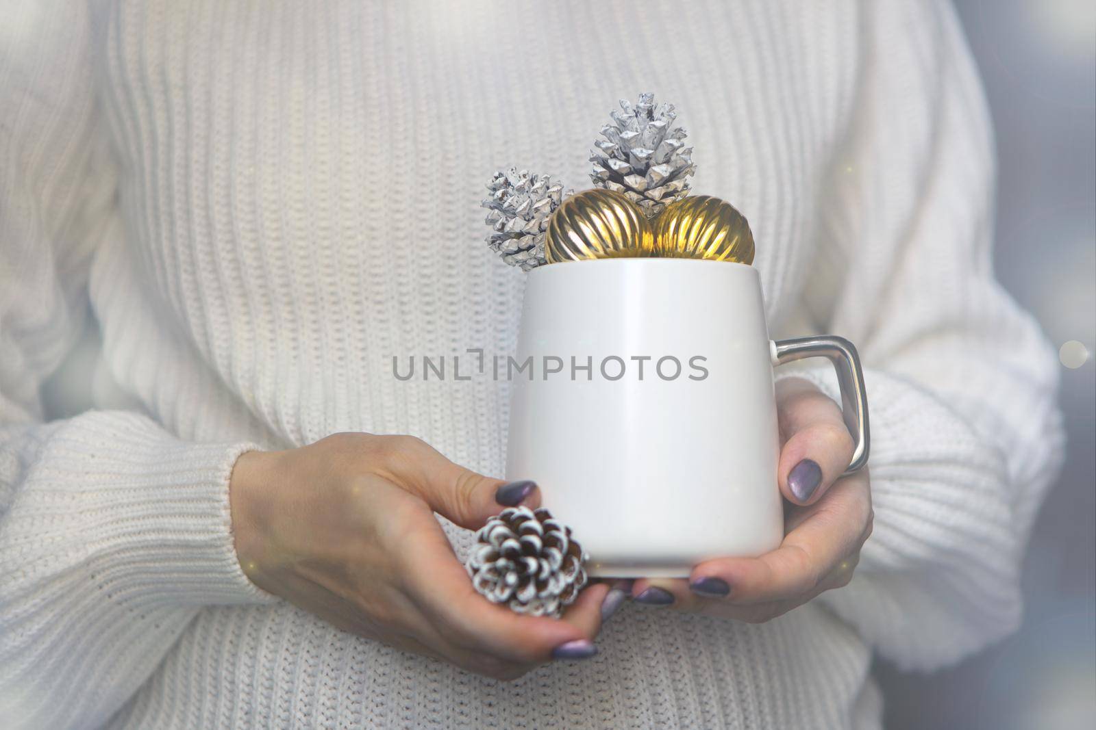 white christmas cup on woman hands with pine cones and golden balls -winter mug close up for new year time concept