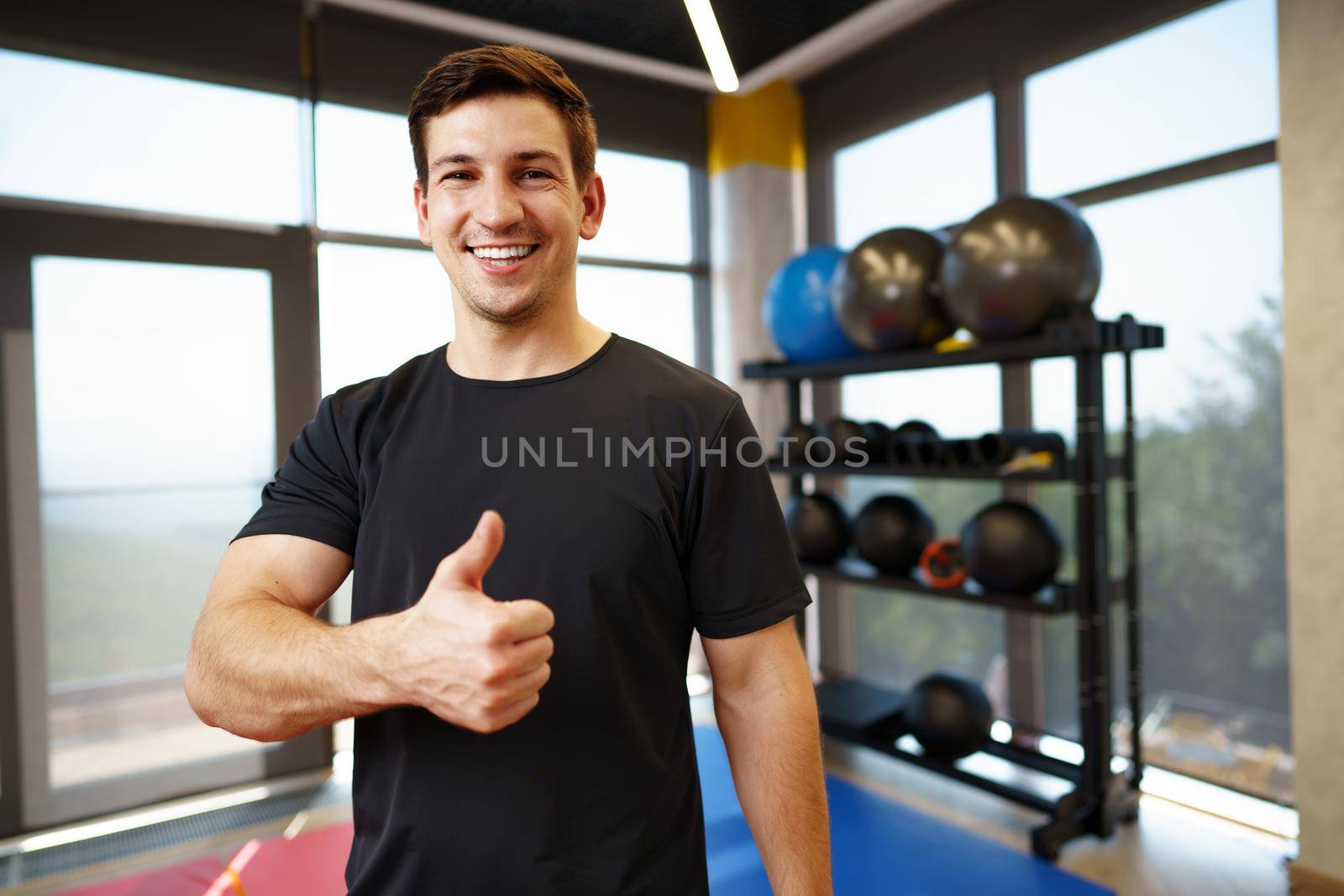 Portrait of a young handsome fitness trainer in a gym, close up