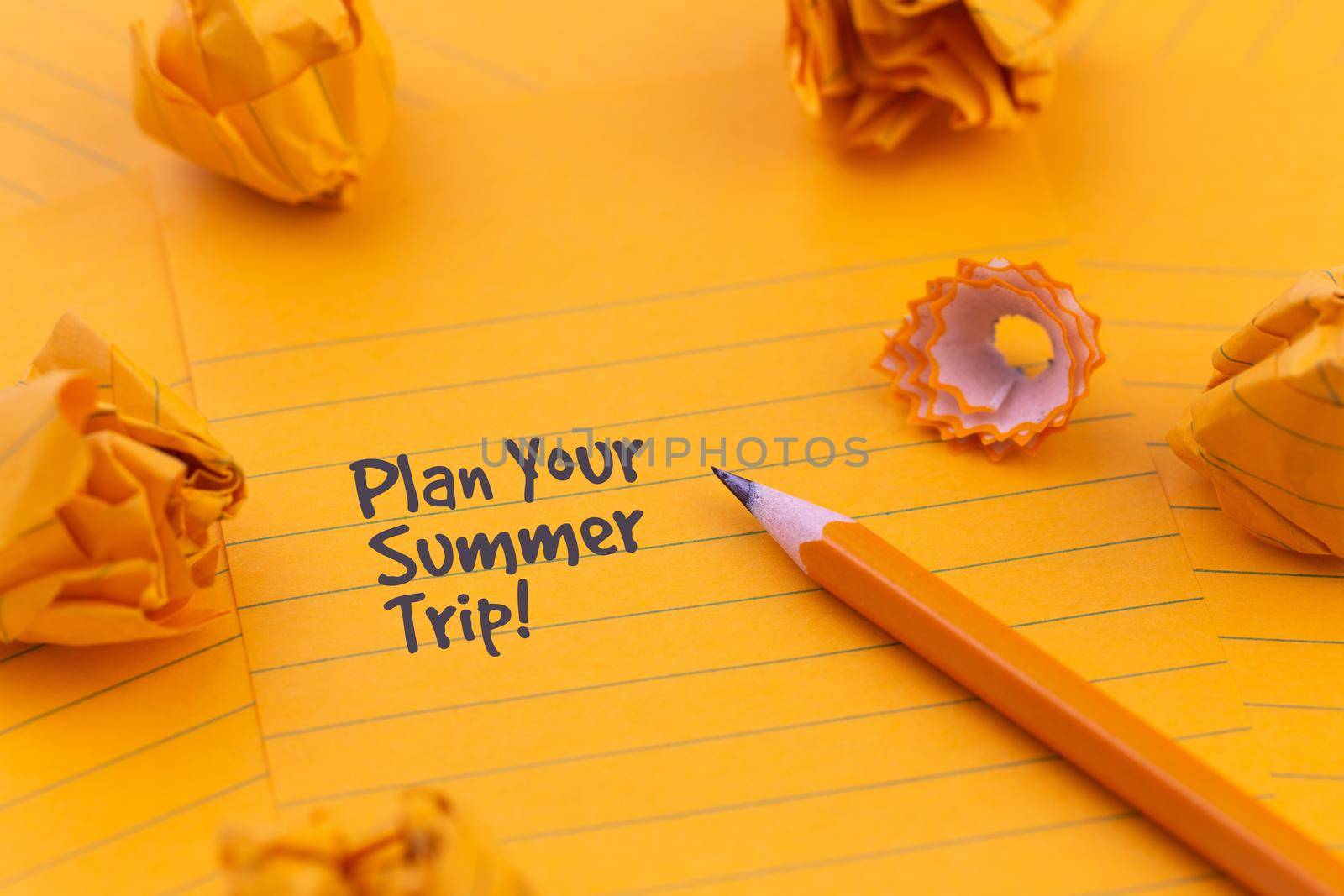 Concept Hello summer or planning a summer trip. Orange sheets of paper, pencil and other stationery objects.