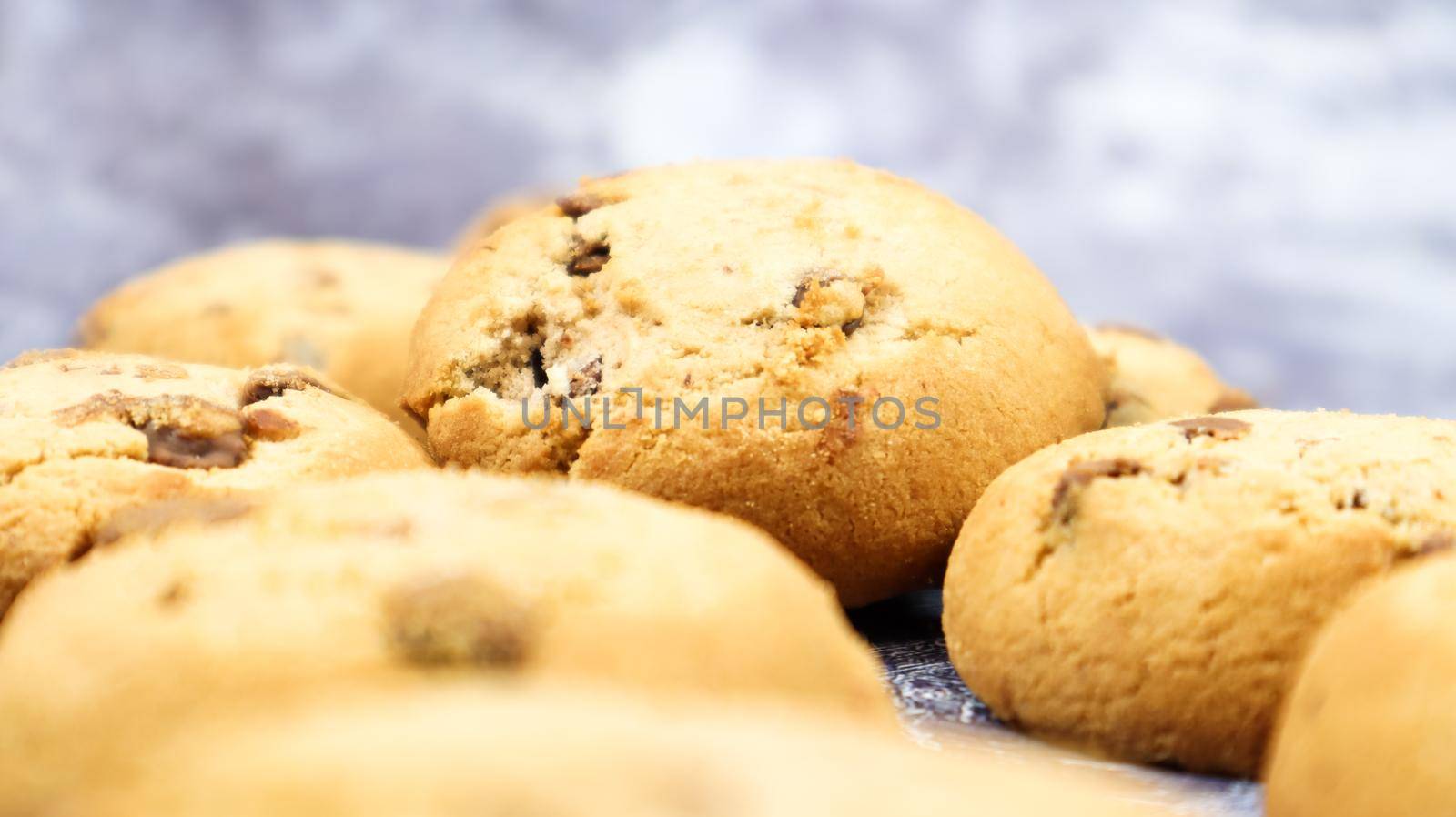Soft, freshly baked chocolate chip cookies on a gray marble kitchen countertop. American traditional sweet pastry pastry, delicious homemade dessert. Culinary background. Selective focus.