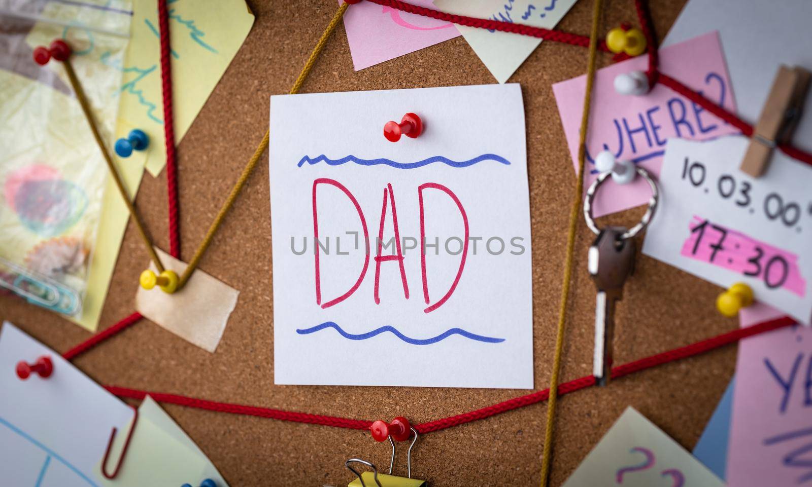 Dad search concept. Close-up view of a detective board with evidence. In the center is a white sheet attached with a red pin with the text Dad.
