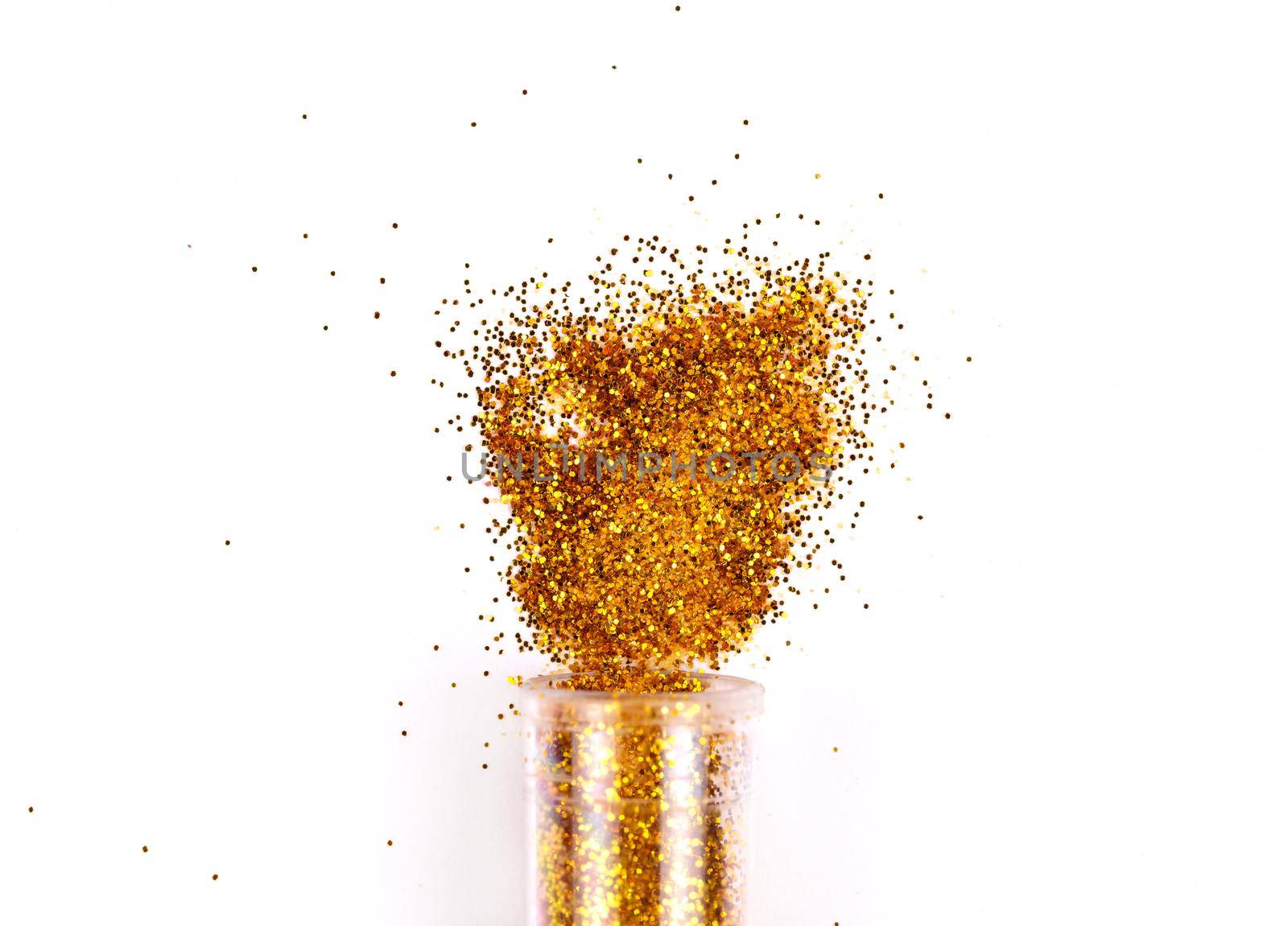 Jar with spilled gold glitter, shiny eyeshadows on white background.