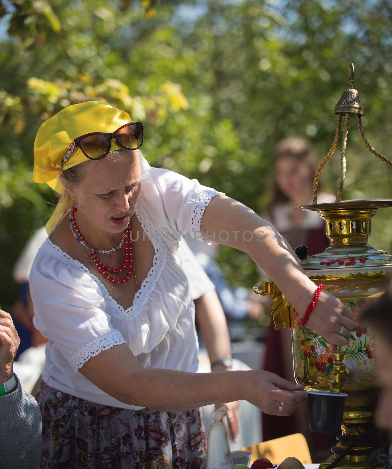 20 August 2018, Krasnovidovo, Russia - mature woman pours tea from a samovar. folk fair