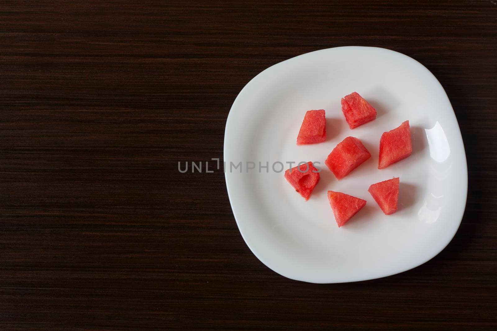 Slices of watermelon on a white plate on a dark background