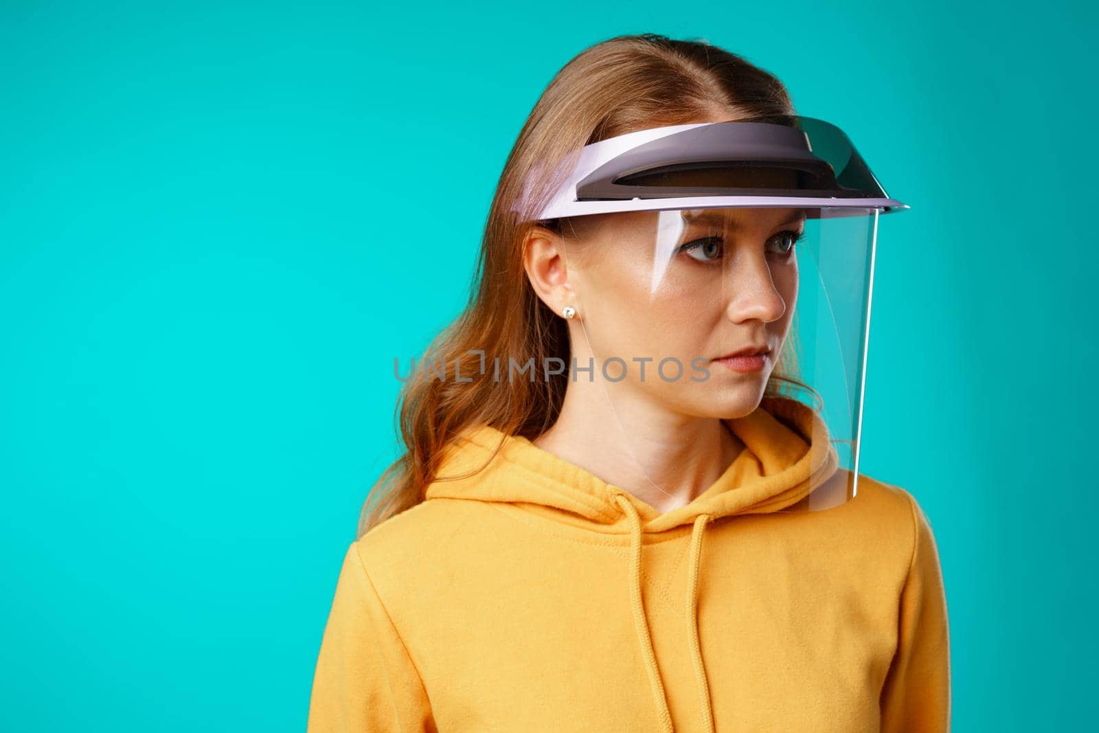 Young woman wearing medical protective face shield against blue background